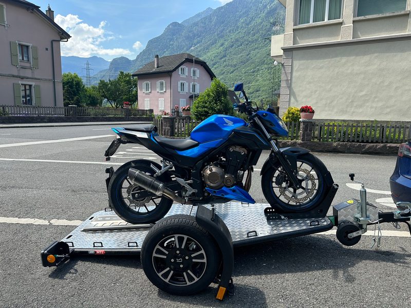 Moto bleue sanglée sur le plancher aluminium de la remorque Lorries MT-1, vue de profil